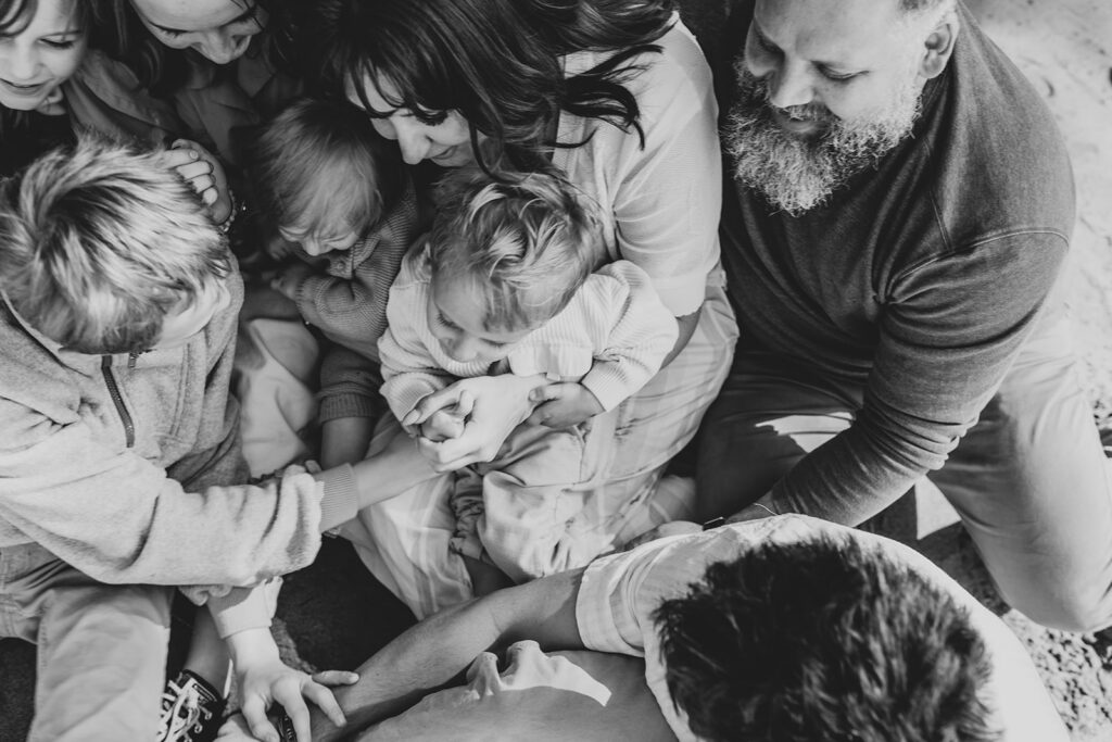 Black and white image taken from above of a family sitting on the beach together