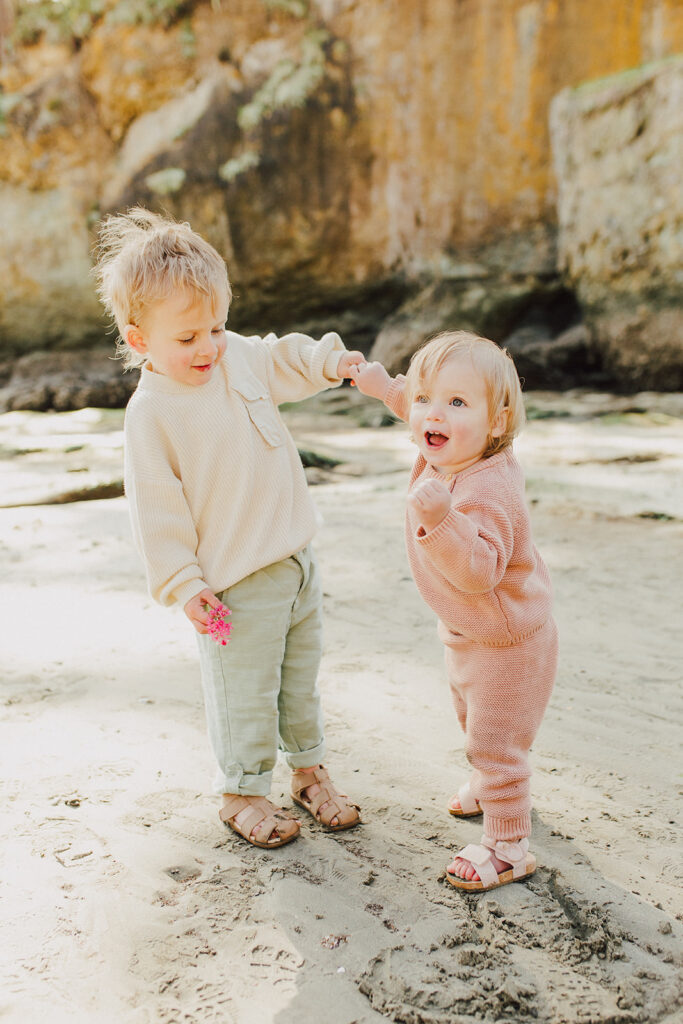 A toddler boy and girl dancing on the beach
