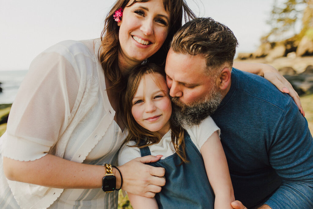 A mom and dad with their daughter on the beach.