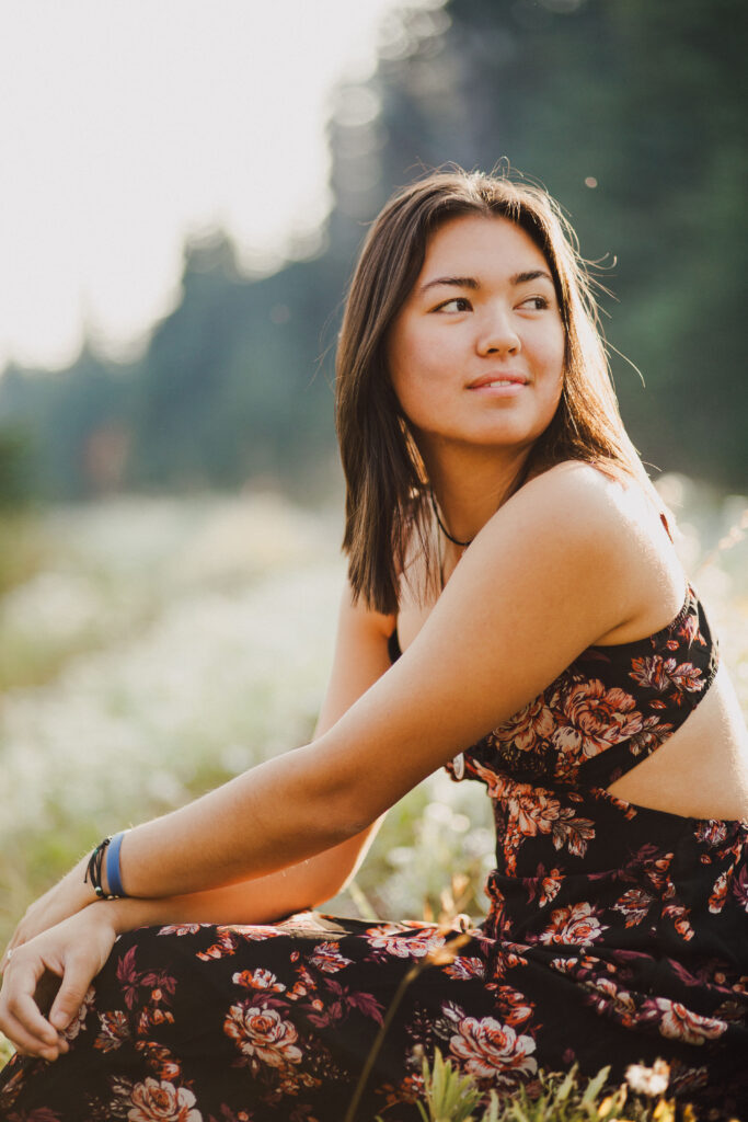 A teenage girl sitting and smiling over her shoulder