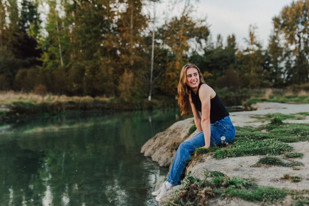 Girl sits on a river bank looking over her shoulder