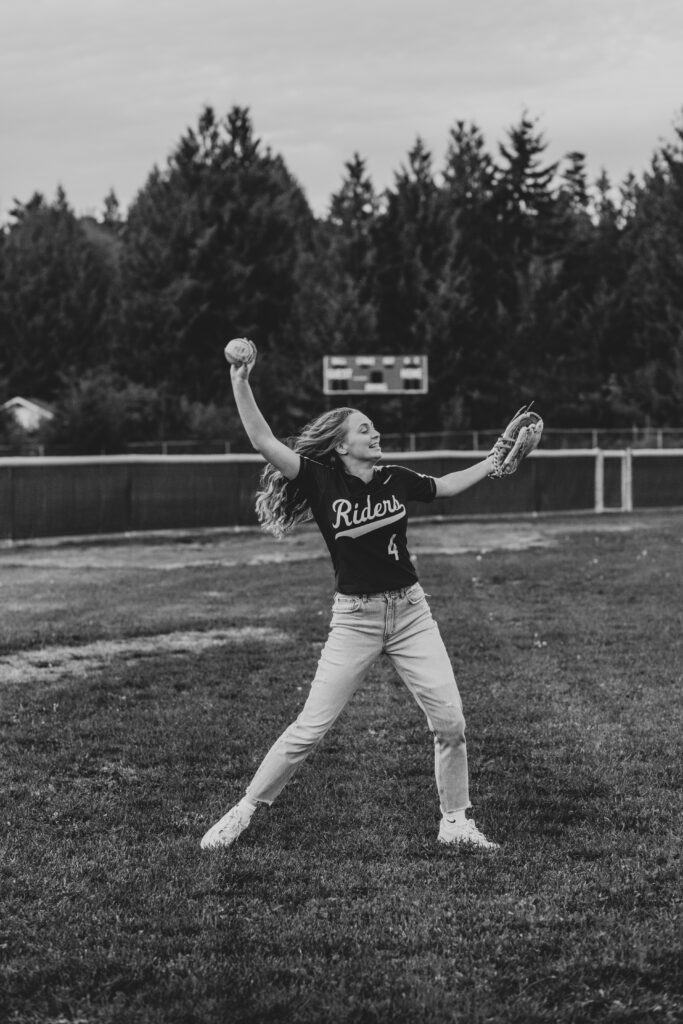 Teenage girl winding up for a softball pitch wearing a Port Angeles Rough Riders jersey