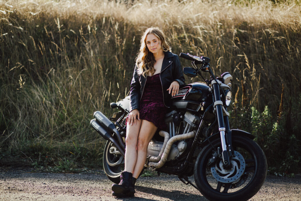 A girl leaning up against her motorcycle