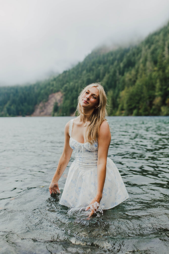 A teenage girl in a white sundress standing in Lake Crescent.
