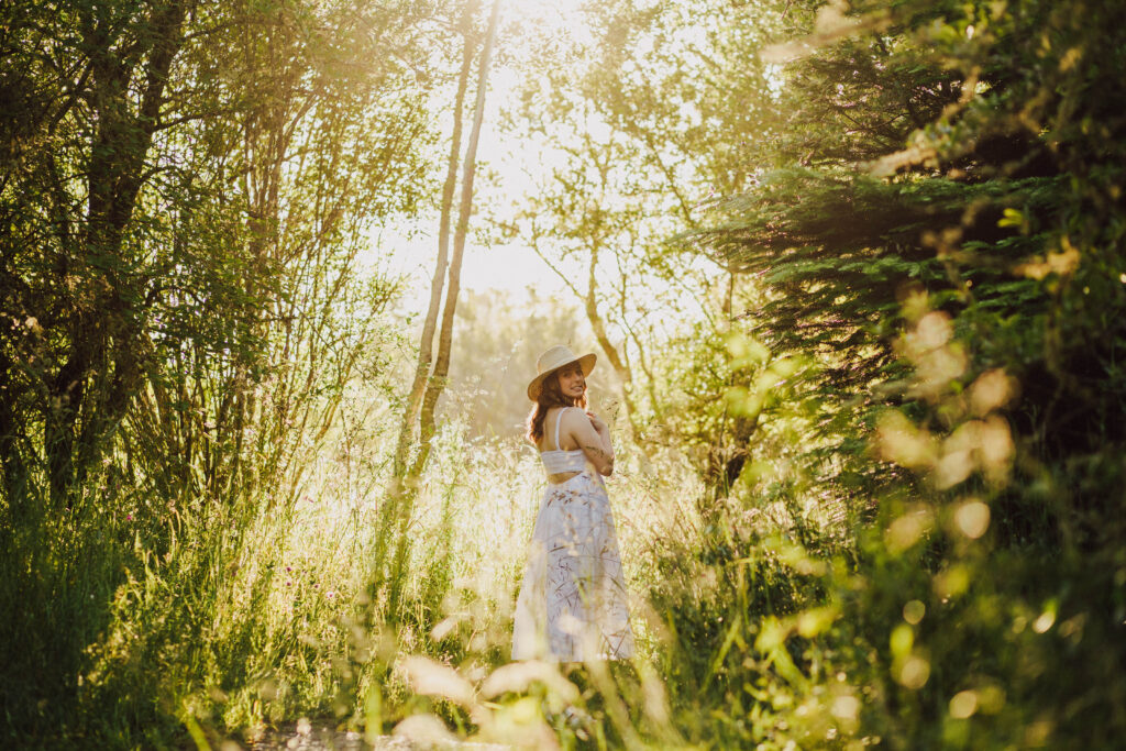 High school senior girl in the woods with a glowy sunset
