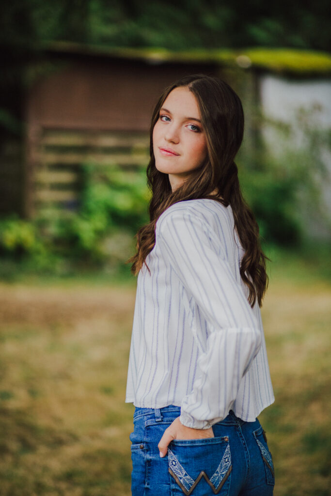 A girl with brown hair looks over her shoulder at the camera