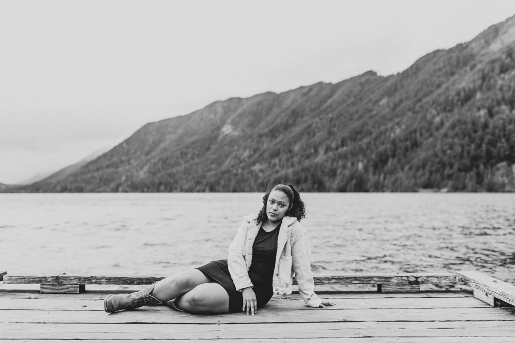 Black and white image of girl sitting on the dock at Lake Crescent