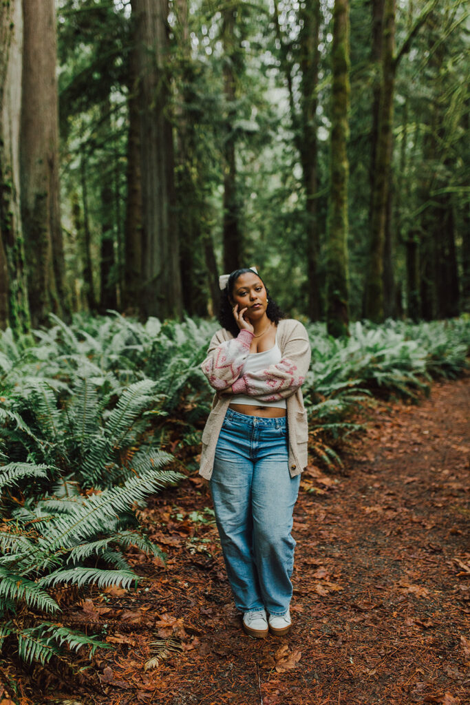 Teenage girl standing in the forest with lots of ferns in the background