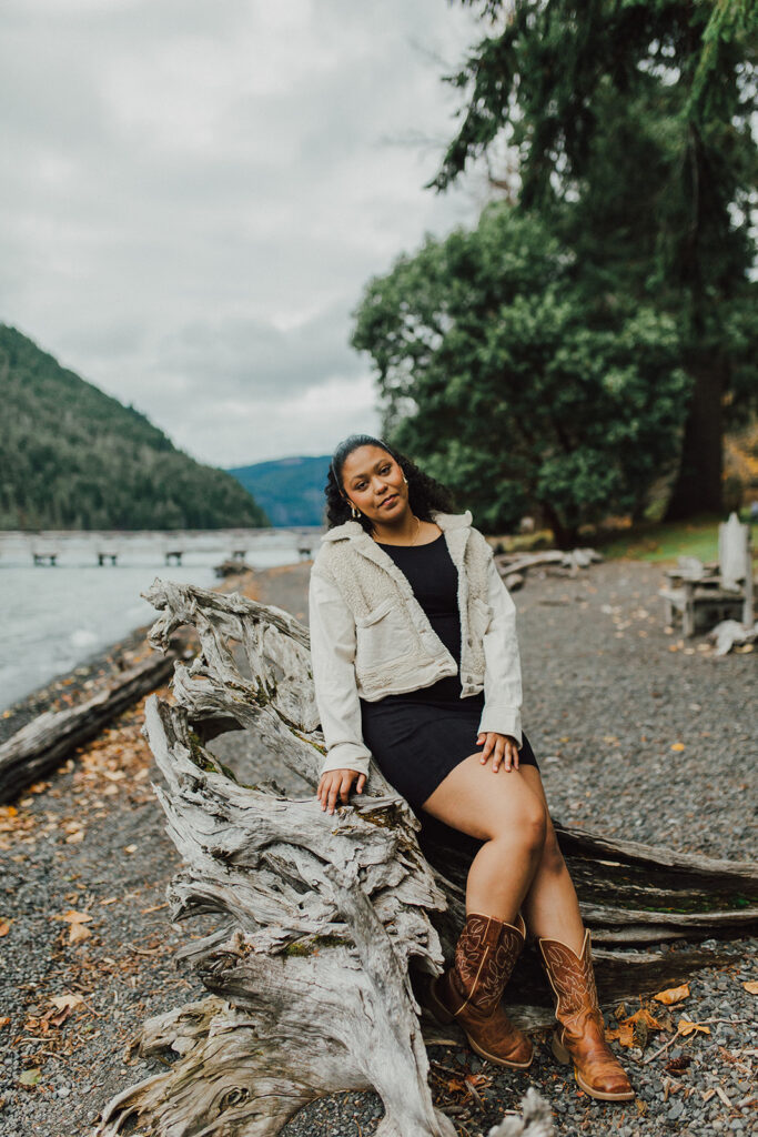 High School senior sitting on driftwood with Lake Crescent in the background