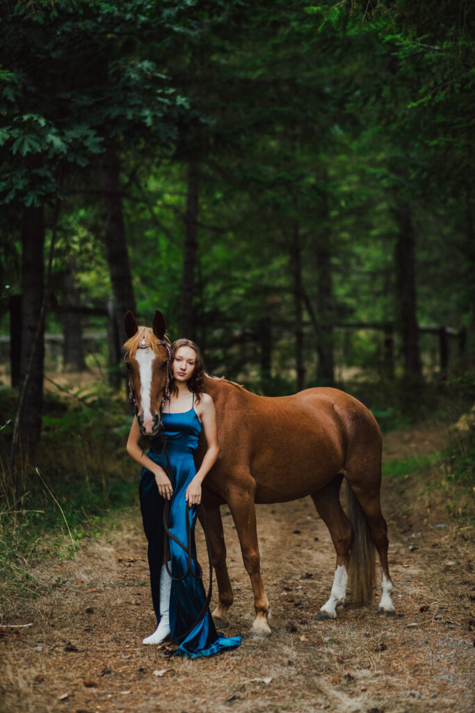 A girl in a fancy silk dress posing with her horse